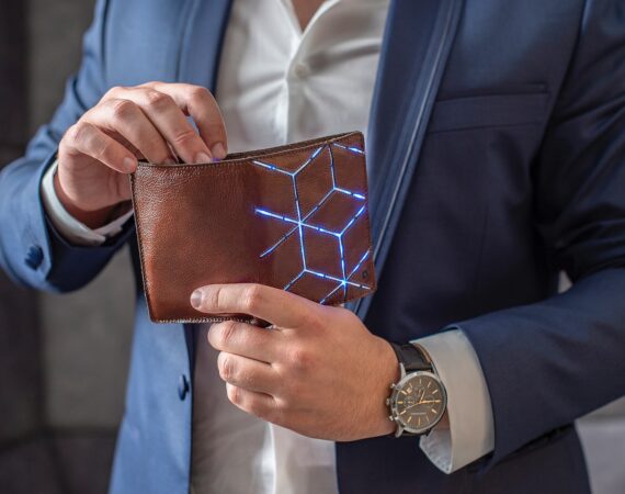 man in blue suit jacket holding brown leather wallet